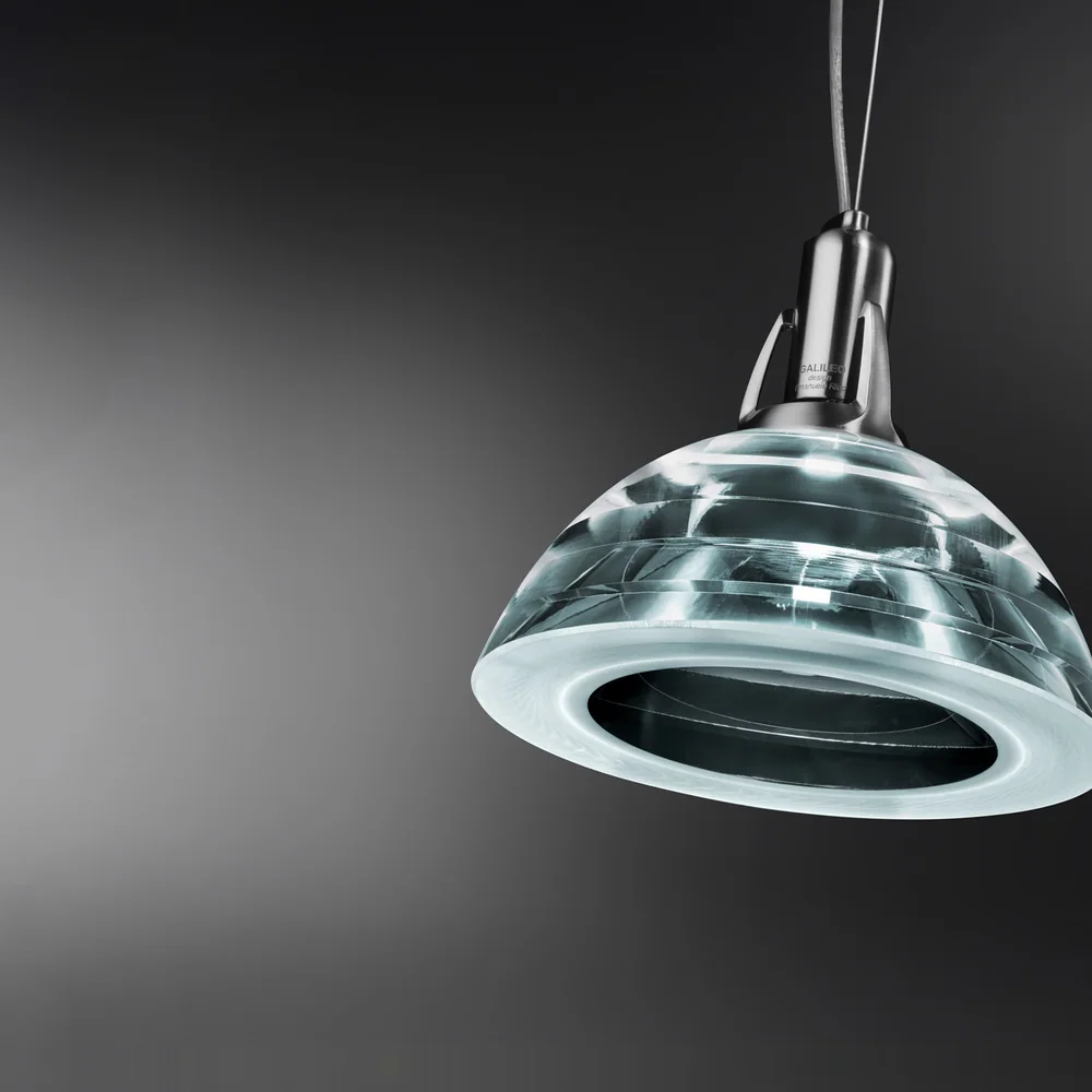 Lumina: Kompakter gläserner Leuchtenkörper mit optisch geschichteter Kontur an zwei feinen Aufhängungen.