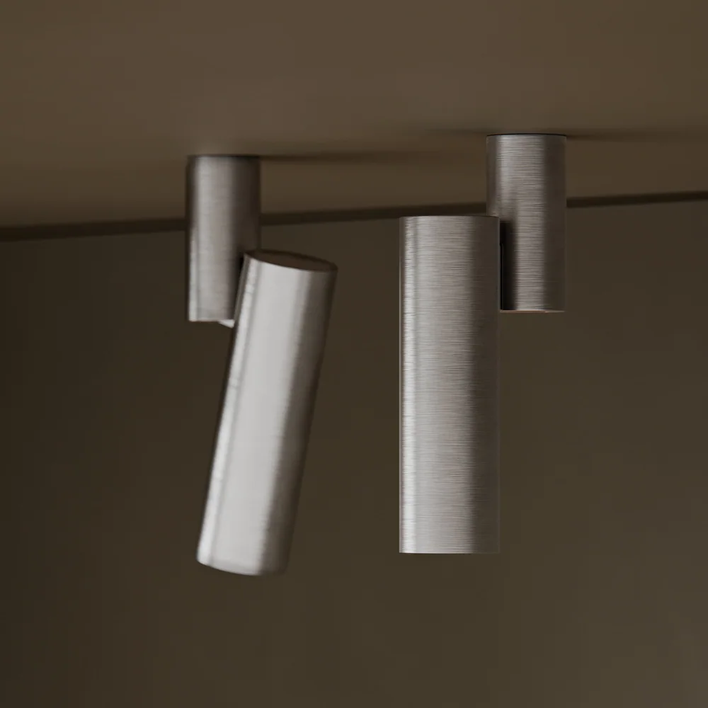 Modular Lighting Instruments: Mehrere zylindrische Strahler an einer hellen Decke, teilweise schräg ausgerichtet.