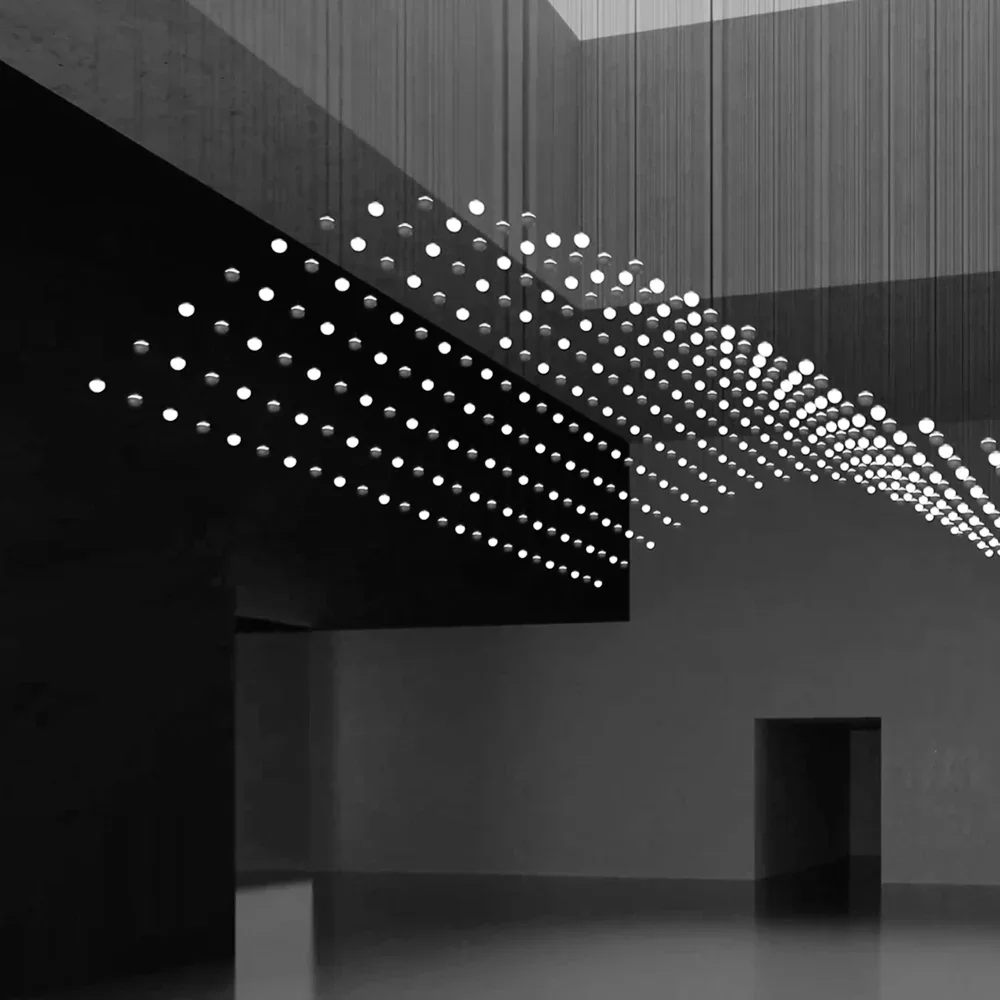 Prolicht: Viele kleine runde Leuchtpunkte bilden eine räumlich gestaffelte hängende Lichtstruktur vor dunklem Hintergrund.