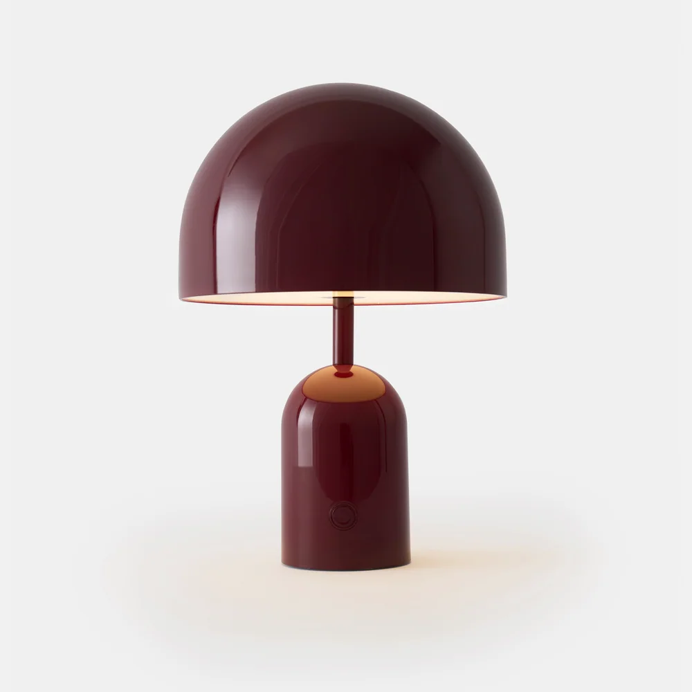 Tom Dixon: Kleine tragbare Leuchte mit breitem kuppelförmigem Schirm und rundem Fuß vor weißem Hintergrund.